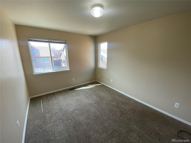 carpeted spare room featuring visible vents and baseboards