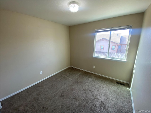 unfurnished room with visible vents, dark carpet, and baseboards