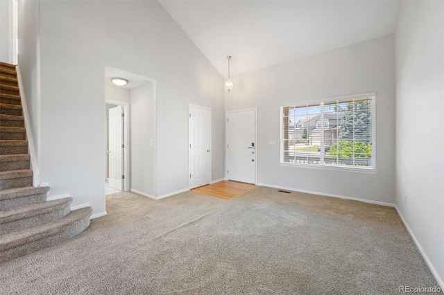 unfurnished room with light colored carpet and high vaulted ceiling