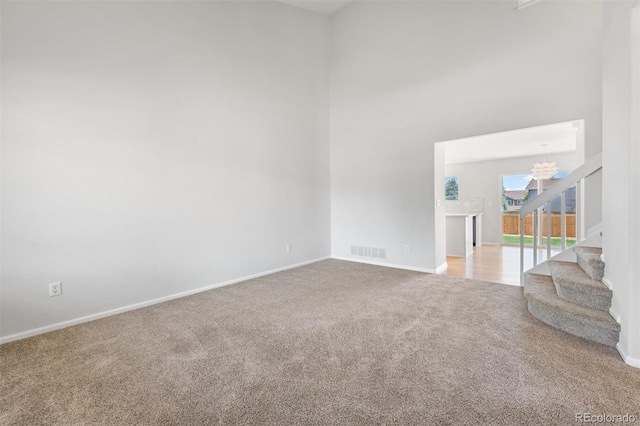 unfurnished room featuring light colored carpet, a chandelier, and a towering ceiling