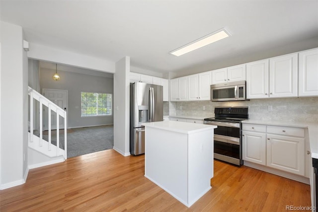 kitchen with appliances with stainless steel finishes, a center island, white cabinetry, and light wood-type flooring