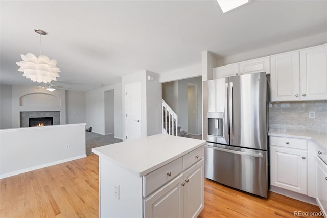 kitchen with decorative backsplash, light hardwood / wood-style floors, stainless steel fridge with ice dispenser, and white cabinetry