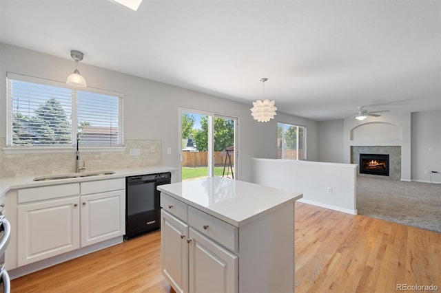 kitchen featuring tasteful backsplash, sink, dishwashing machine, light carpet, and hanging light fixtures