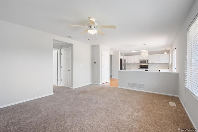 unfurnished living room featuring ceiling fan and light carpet