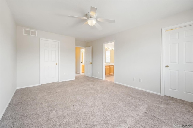 unfurnished bedroom with light colored carpet, ensuite bath, and ceiling fan