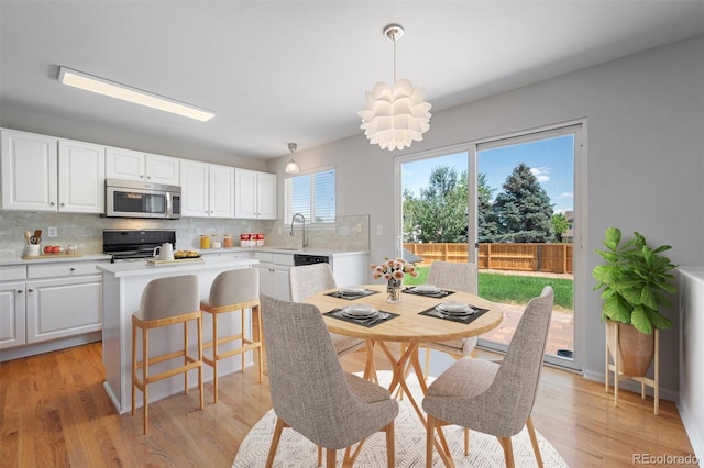 dining room with sink, a notable chandelier, and light hardwood / wood-style floors