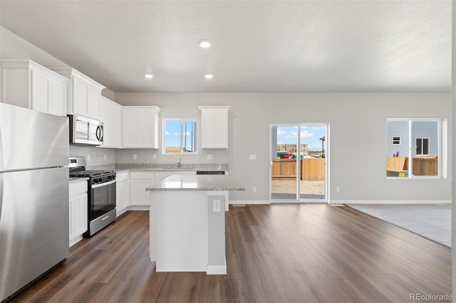 kitchen featuring a sink, dark wood-style flooring, stainless steel appliances, and a kitchen island