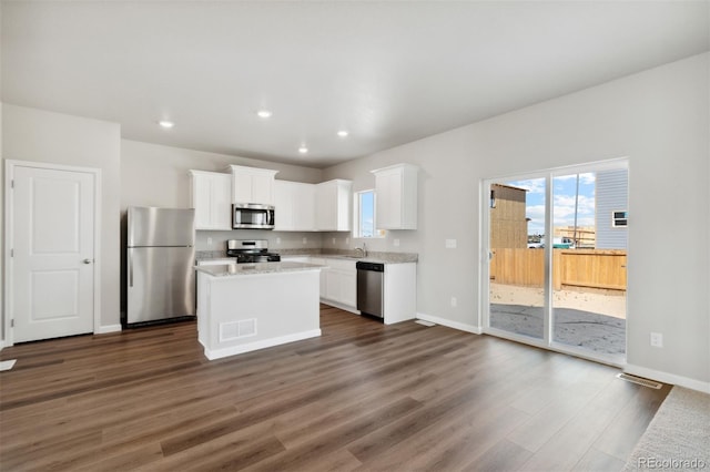 kitchen with baseboards, dark wood finished floors, white cabinetry, a kitchen island, and appliances with stainless steel finishes