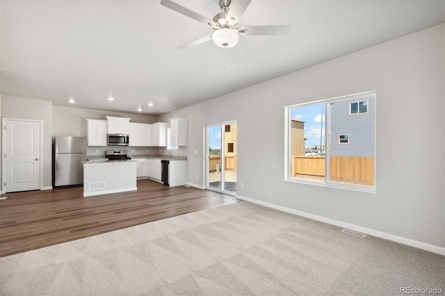 unfurnished living room featuring visible vents, recessed lighting, dark colored carpet, a ceiling fan, and baseboards