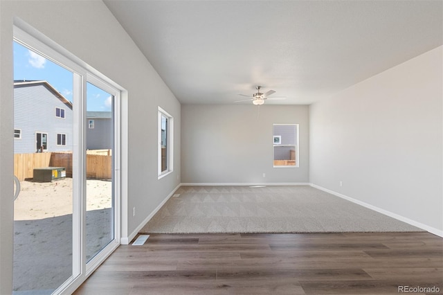 carpeted empty room featuring baseboards, ceiling fan, and wood finished floors