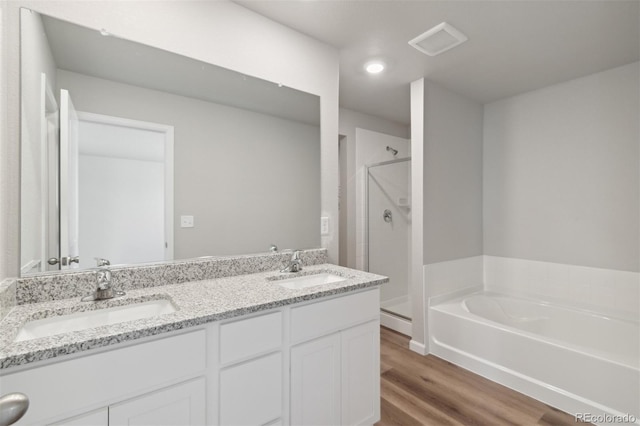 bathroom with a shower stall, a garden tub, a sink, and wood finished floors