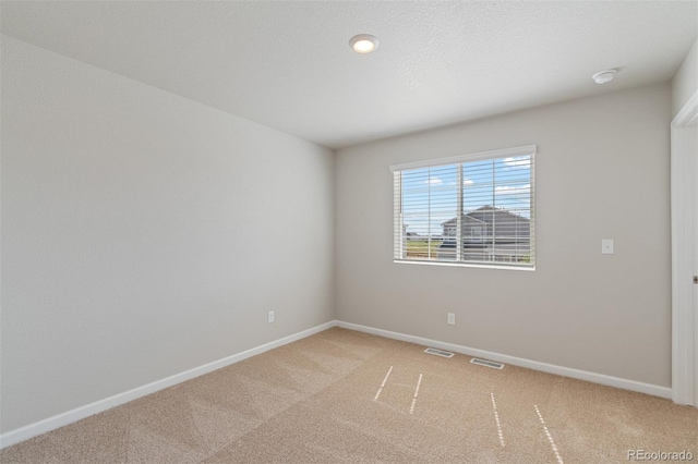 spare room featuring baseboards, visible vents, and light colored carpet