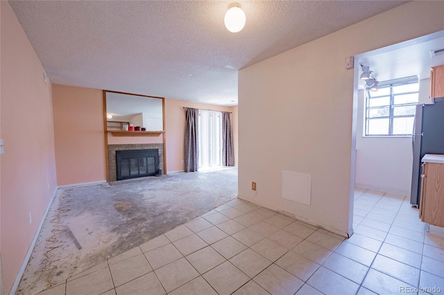 12506 E Cornell Ave Unit 102, Aurora, CO 80014 - unfurnished living room with plenty of natural light, a textured ceiling, light tile patterned floors, a fireplace, and light colored carpet