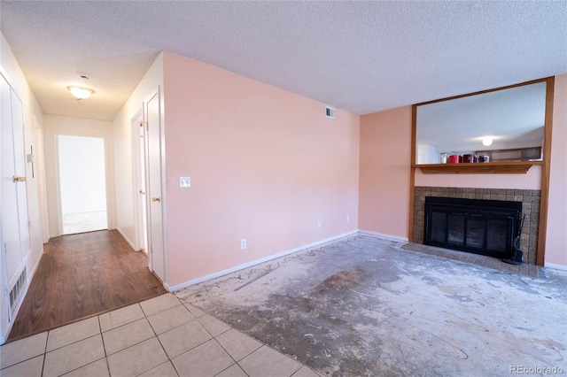 12506 E Cornell Ave Unit 102, Aurora, CO 80014 - unfurnished living room featuring a brick fireplace, a textured ceiling, and tile patterned floors