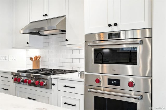 474 S Vine St, Denver, CO 80209 - kitchen featuring extractor fan, stainless steel appliances, white cabinetry, and decorative backsplash