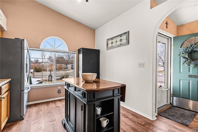 kitchen featuring hardwood / wood-style floors, lofted ceiling, a wealth of natural light, and stainless steel fridge