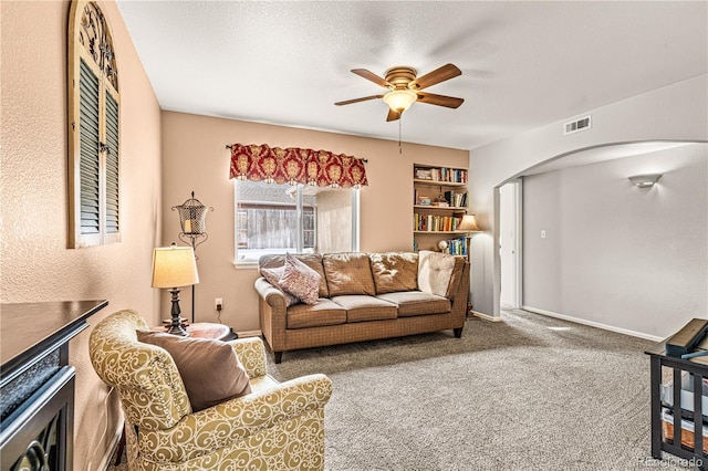 carpeted living room featuring ceiling fan and a textured ceiling