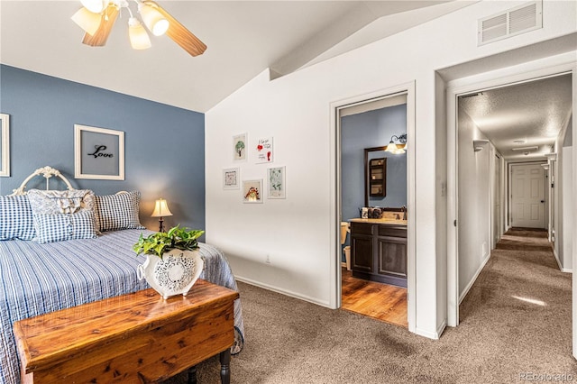 carpeted bedroom featuring ceiling fan, lofted ceiling, and ensuite bath