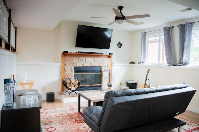 7961 Jared Way, Littleton, CO 80125 - living room featuring wood finished floors, a ceiling fan, and a stone fireplace