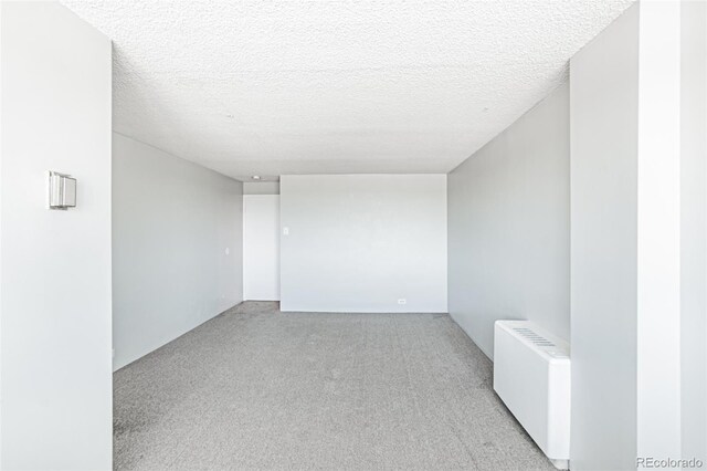 2225 Buchtel Blvd Unit 1005, Denver, CO 80210 - empty room featuring radiator heating unit, light colored carpet, and a textured ceiling