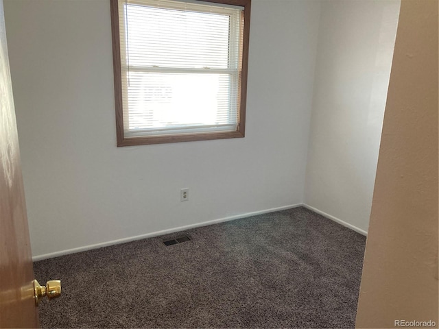 unfurnished room featuring dark colored carpet, visible vents, and baseboards