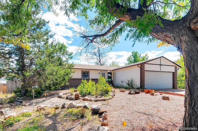 ranch-style house featuring an attached garage, driveway, fence, and brick siding