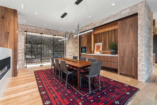 dining room with light hardwood / wood-style floors and a stone fireplace