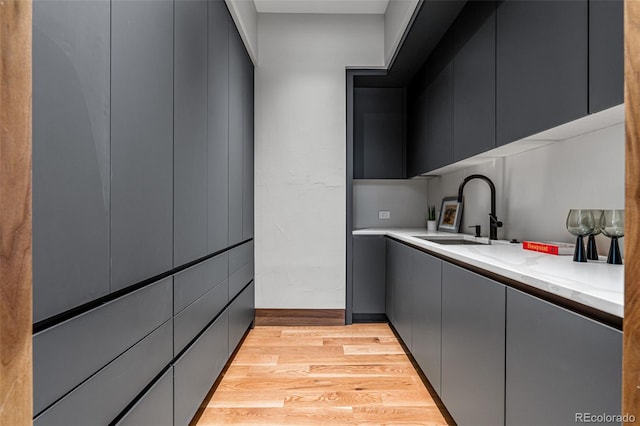 kitchen featuring light stone counters, sink, and light wood-type flooring