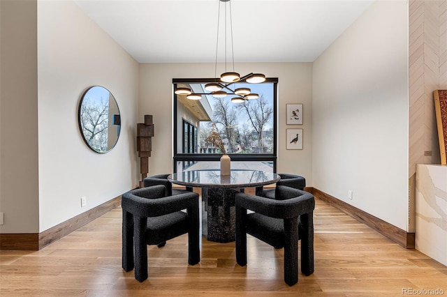 dining space featuring light wood-type flooring and a notable chandelier