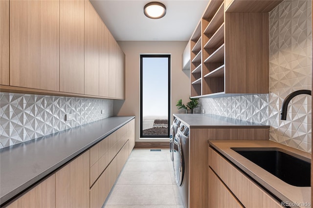 laundry room with cabinets, light tile patterned floors, sink, and washing machine and clothes dryer