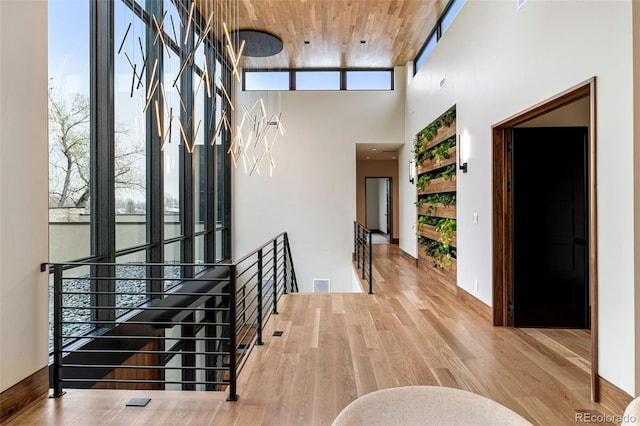 hall featuring a towering ceiling, hardwood / wood-style flooring, and wood ceiling