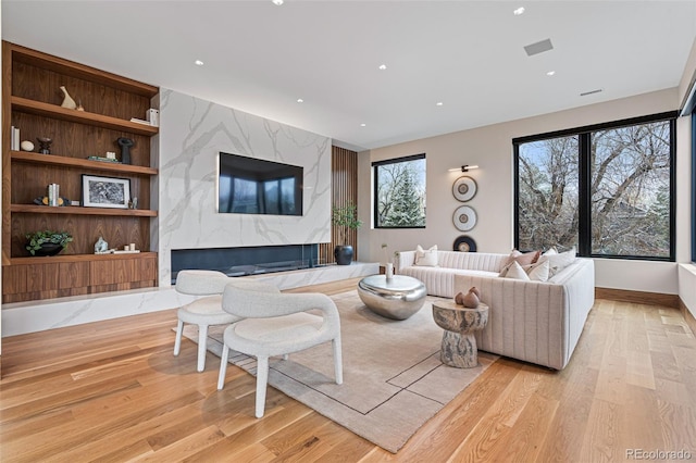 living room featuring a high end fireplace and light hardwood / wood-style flooring