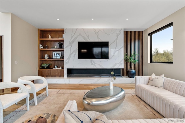 living room featuring a fireplace, built in features, and light hardwood / wood-style floors