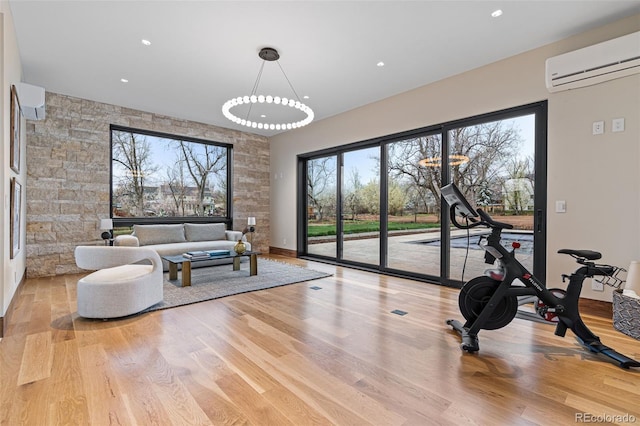 exercise area featuring an AC wall unit, plenty of natural light, and light hardwood / wood-style floors