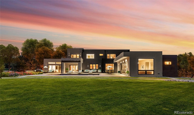 back house at dusk with a yard and an outdoor hangout area