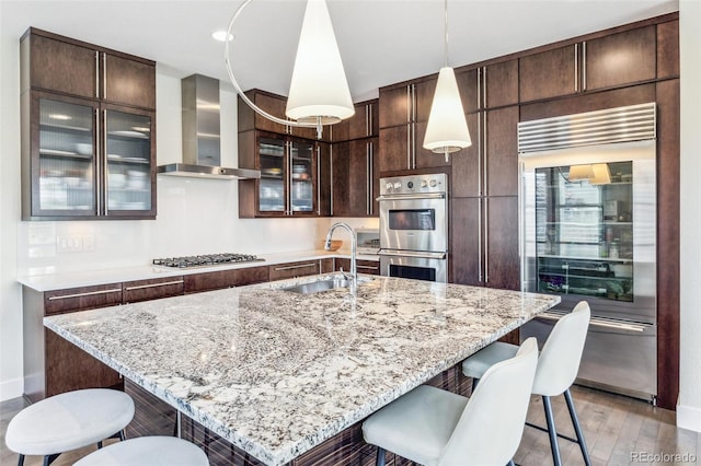 9244 E 37th Ave, Denver, CO 80238 - kitchen with ventilation hood, appliances with stainless steel finishes, a breakfast bar, dark brown cabinets, and recessed lighting