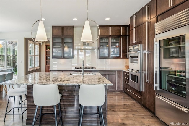 9244 E 37th Ave, Denver, CO 80238 - kitchen with appliances with stainless steel finishes, dark wood-style floors, dark brown cabinets, glass insert cabinets, and recessed lighting
