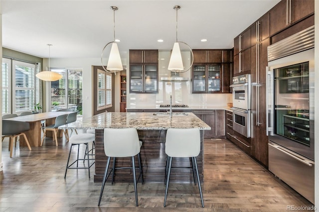 9244 E 37th Ave, Denver, CO 80238 - kitchen featuring appliances with stainless steel finishes, island exhaust hood, a center island with sink, dark brown cabinets, and recessed lighting
