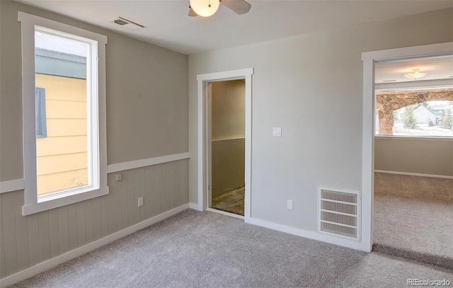 unfurnished bedroom featuring light carpet, ceiling fan, and wooden walls