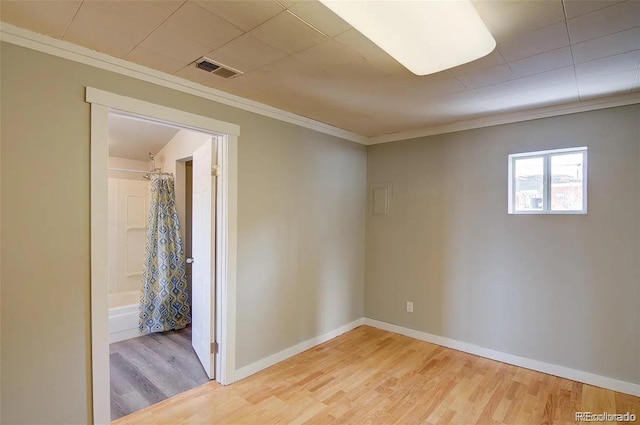 spare room with light hardwood / wood-style floors and crown molding