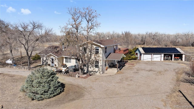 view of front facade featuring an outbuilding, a garage, solar panels, fence, and dirt driveway