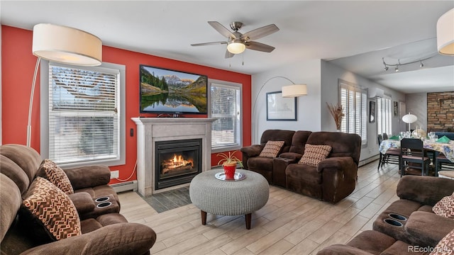 living area featuring a baseboard heating unit, a lit fireplace, and wood tiled floor