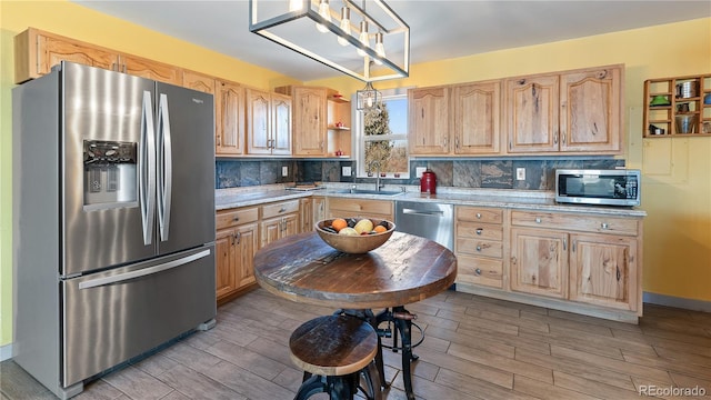 kitchen featuring stainless steel appliances, light brown cabinets, a sink, and tasteful backsplash