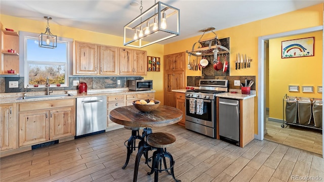 kitchen with light brown cabinets, stainless steel appliances, a sink, and wood tiled floor