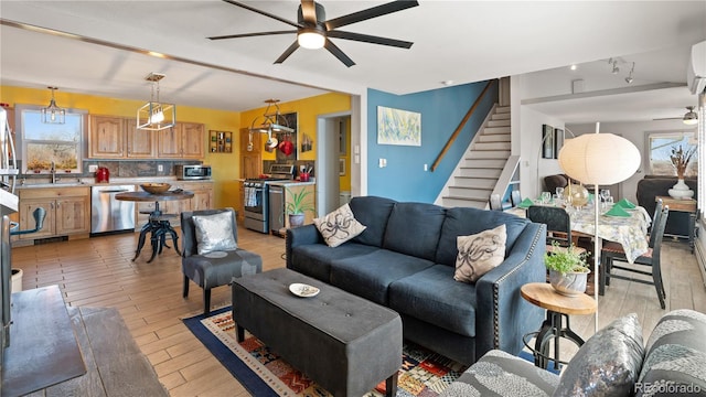 living area featuring a ceiling fan, a healthy amount of sunlight, light wood-style flooring, and stairs