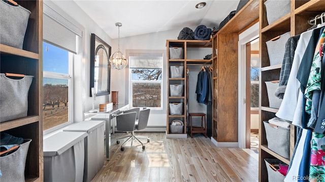 home office with lofted ceiling, light wood-style flooring, and a notable chandelier