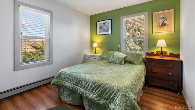 bedroom featuring multiple windows, baseboard heating, and wood finished floors