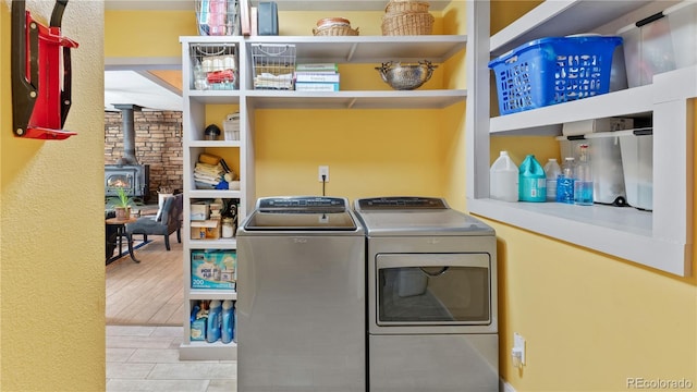 clothes washing area featuring laundry area, wood finished floors, independent washer and dryer, a wood stove, and built in shelves