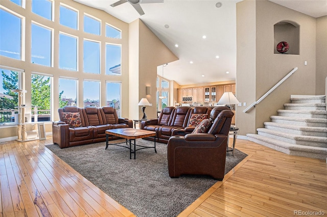 11065 W Rockland Dr, Littleton, CO 80127 - living room featuring a high ceiling, a ceiling fan, light wood-style flooring, baseboards, and stairs