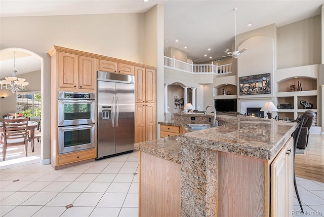 11065 W Rockland Dr, Littleton, CO 80127 - kitchen featuring appliances with stainless steel finishes, a sink, light brown cabinetry, light tile patterned flooring, and high vaulted ceiling